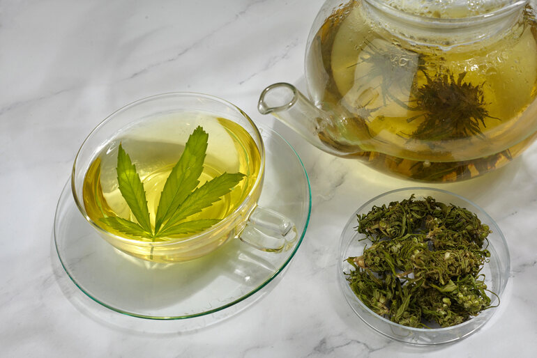 A set of THC tea drinking equipment with a cup full of THC tea