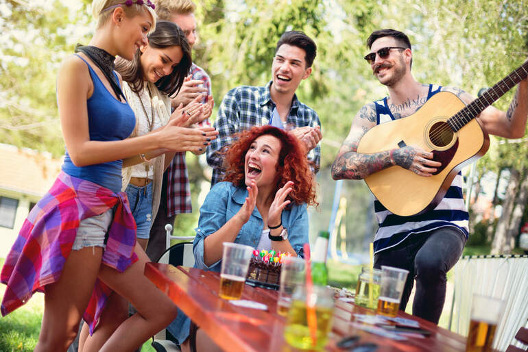 Friends enjoying live music outdoors while relaxing with drinks, celebrating, and having gummies